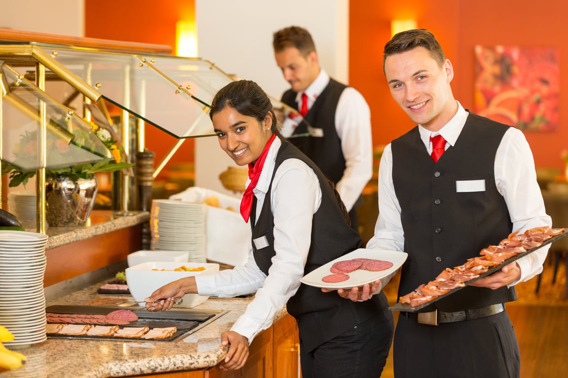 Catering service employees filling buffet at restaurant or hotel